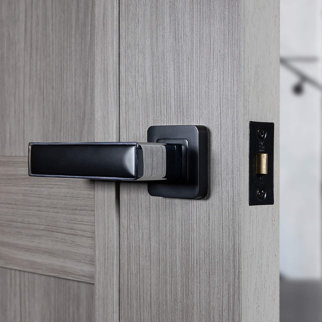 Close-up of a Alto Flat Black & Chrome Plated Square Rose door handle on a grey internal door