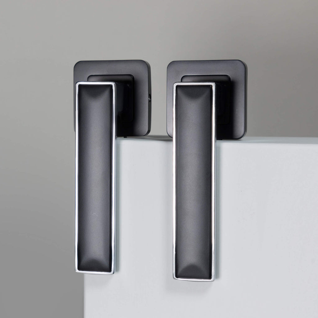 A pair of Alto Flat Black & Chrome Plated Square Rose Handles a grey background