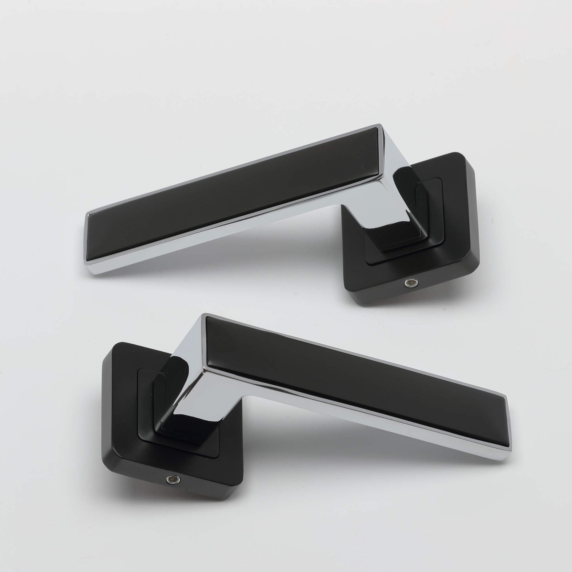 A pair Alto flat black & chrome plated square rose door handles on a white background.