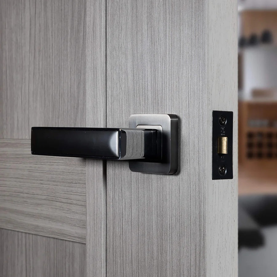 Close-up of an Alto nickle brushed polished chrome modern door handle on a wooden door with a blurred background.