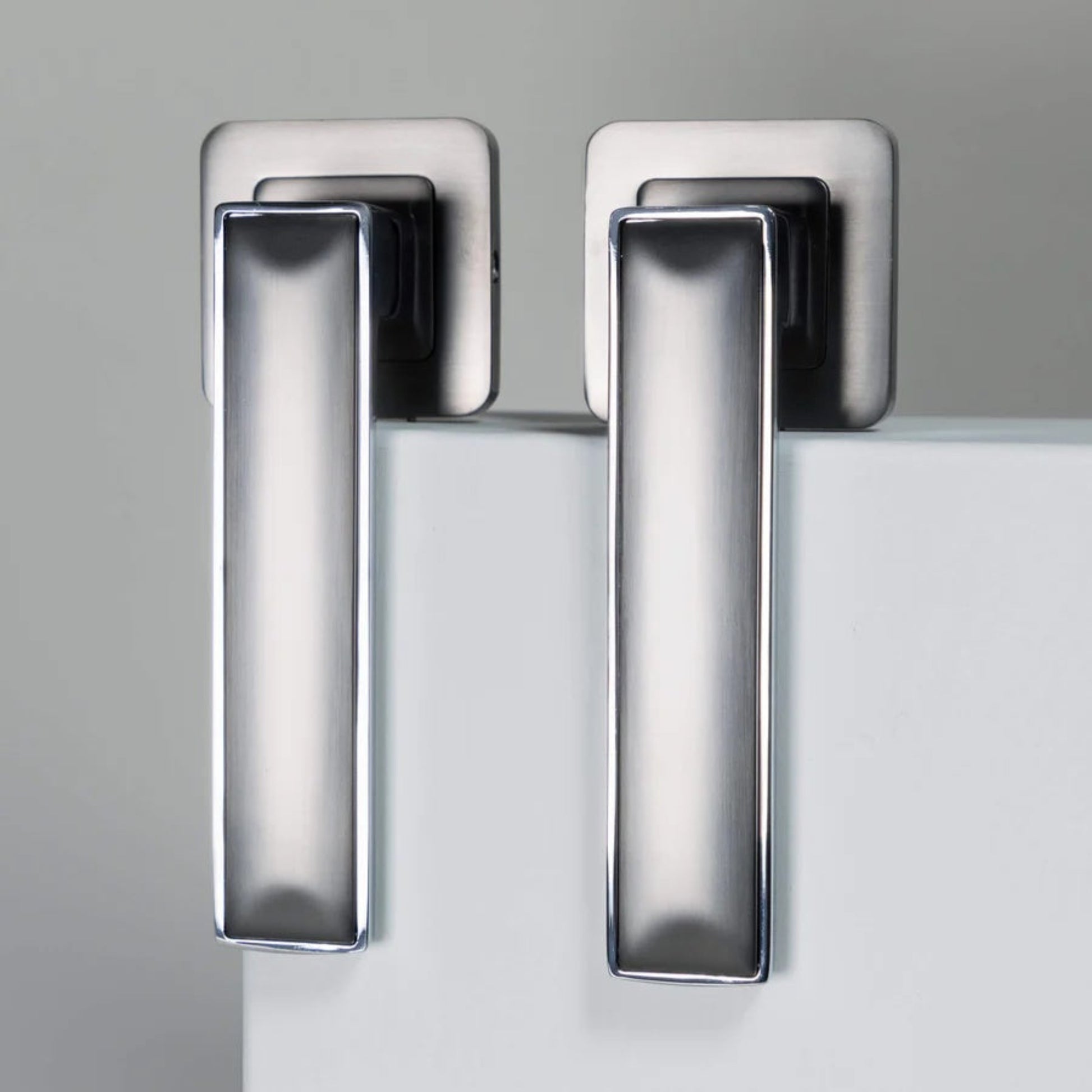 Chrome door handles on a white block with a neutral background