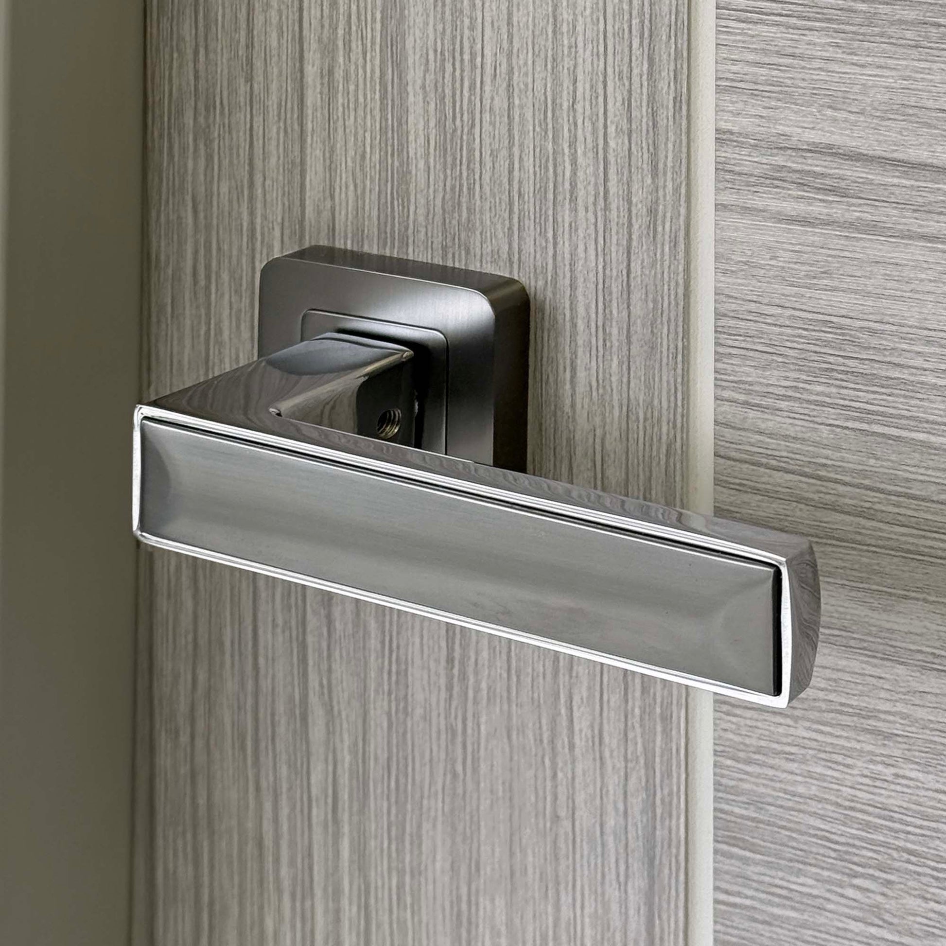 Close up of a  modern Alto Matt Satin Black Door Handle on a grey laminate door