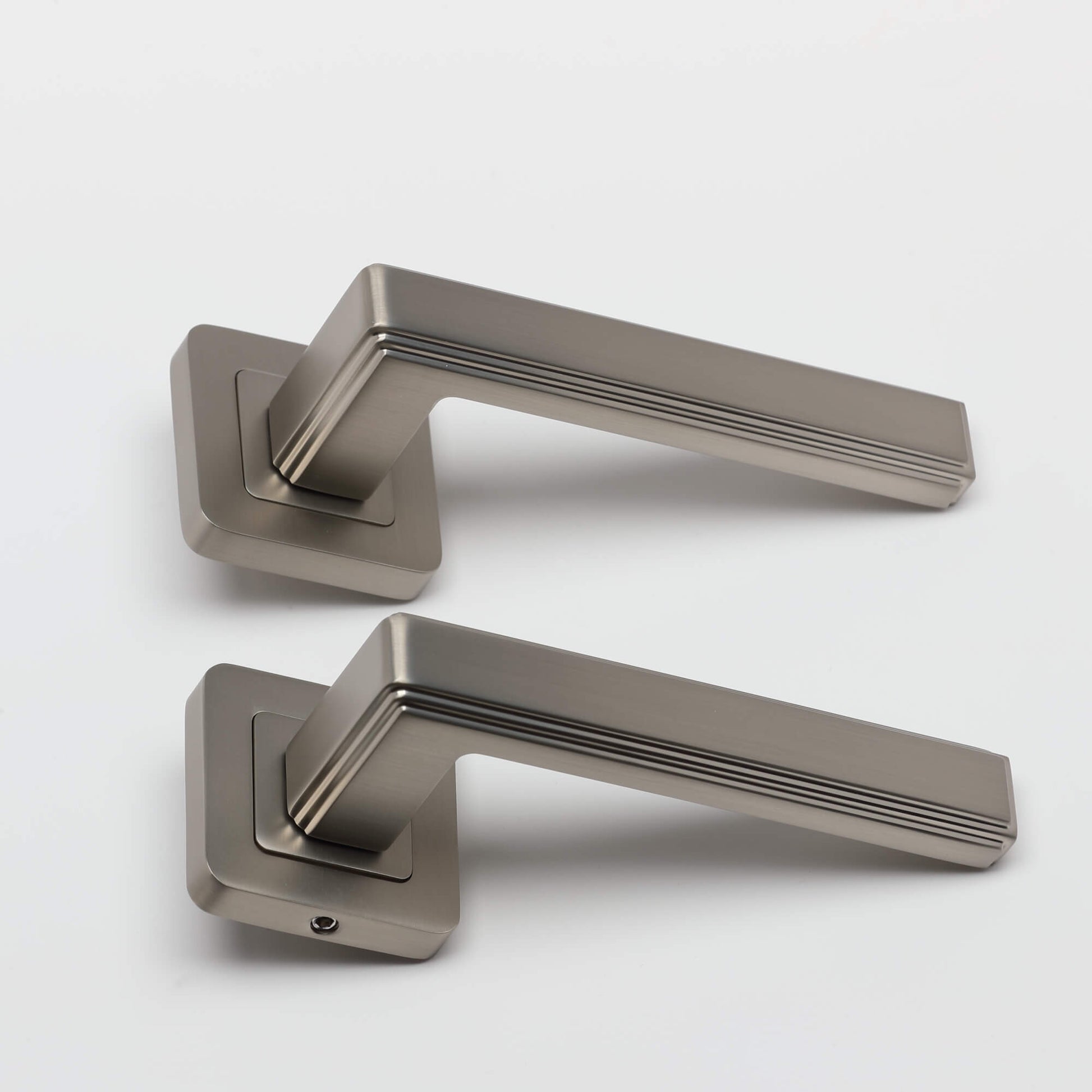 A side view of a pair of Ares Matt Satin Nickel Square Rose door handles on a white background