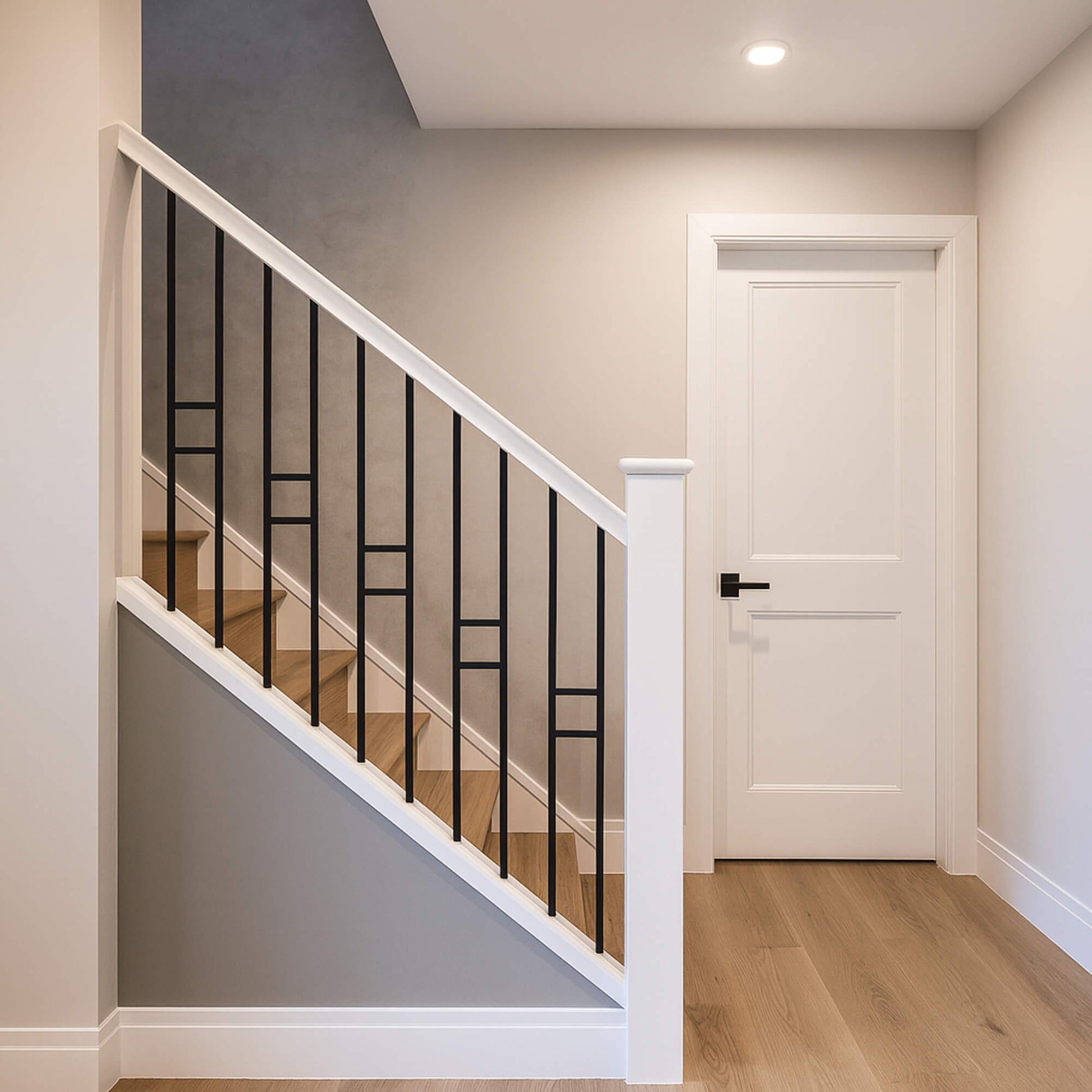 Staircase with black modern square spindles and white primed baseball and  handrail in a home interior.