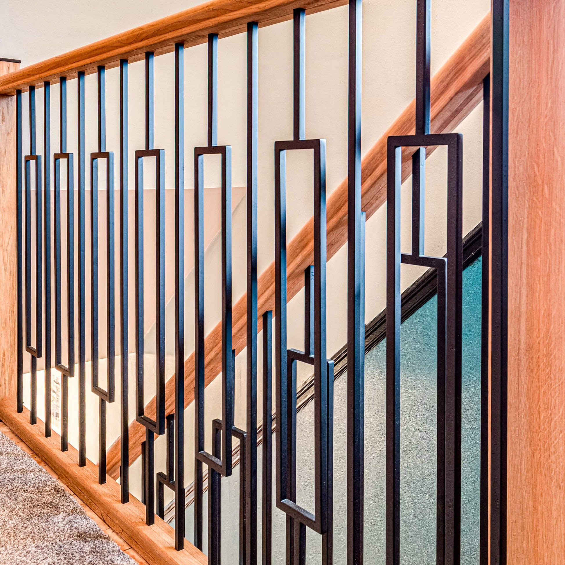 A close-up of an oak staircase railing featuring Black Rectangle Spindles.