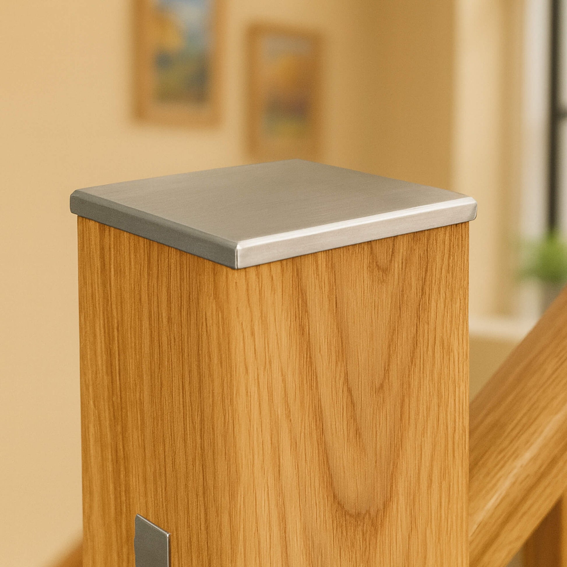 Close-up of a Brushed Nickle Newel Cap in a blurred indoor setting