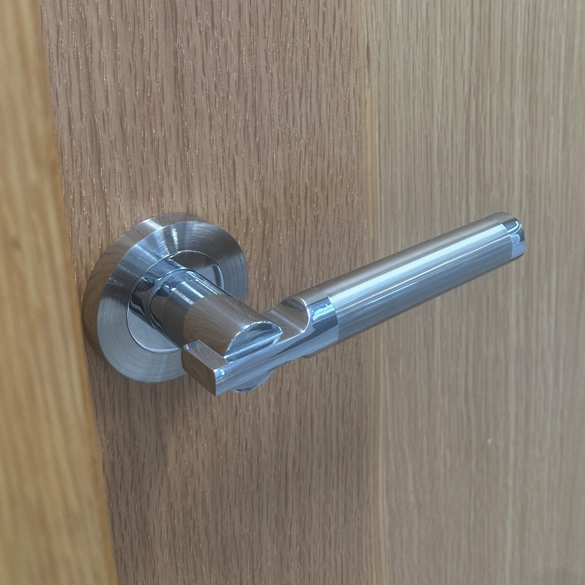 Close-up of a Cumulus Nickel Brushed & Polished Chrome Handle on a wooden door
