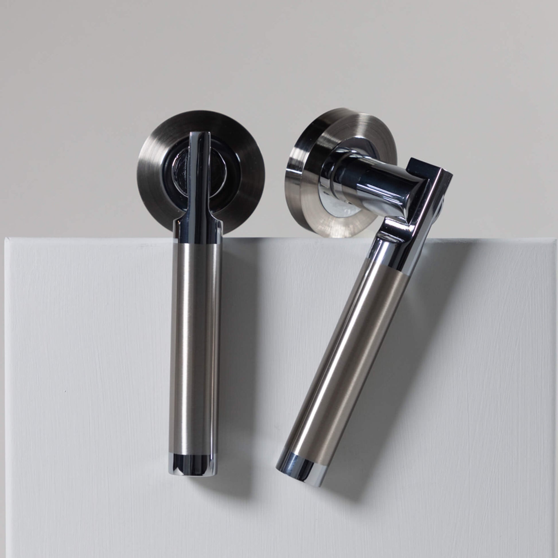 Pair of Cumulus Nickel Brushed & Polished Chrome door handles on a grey background