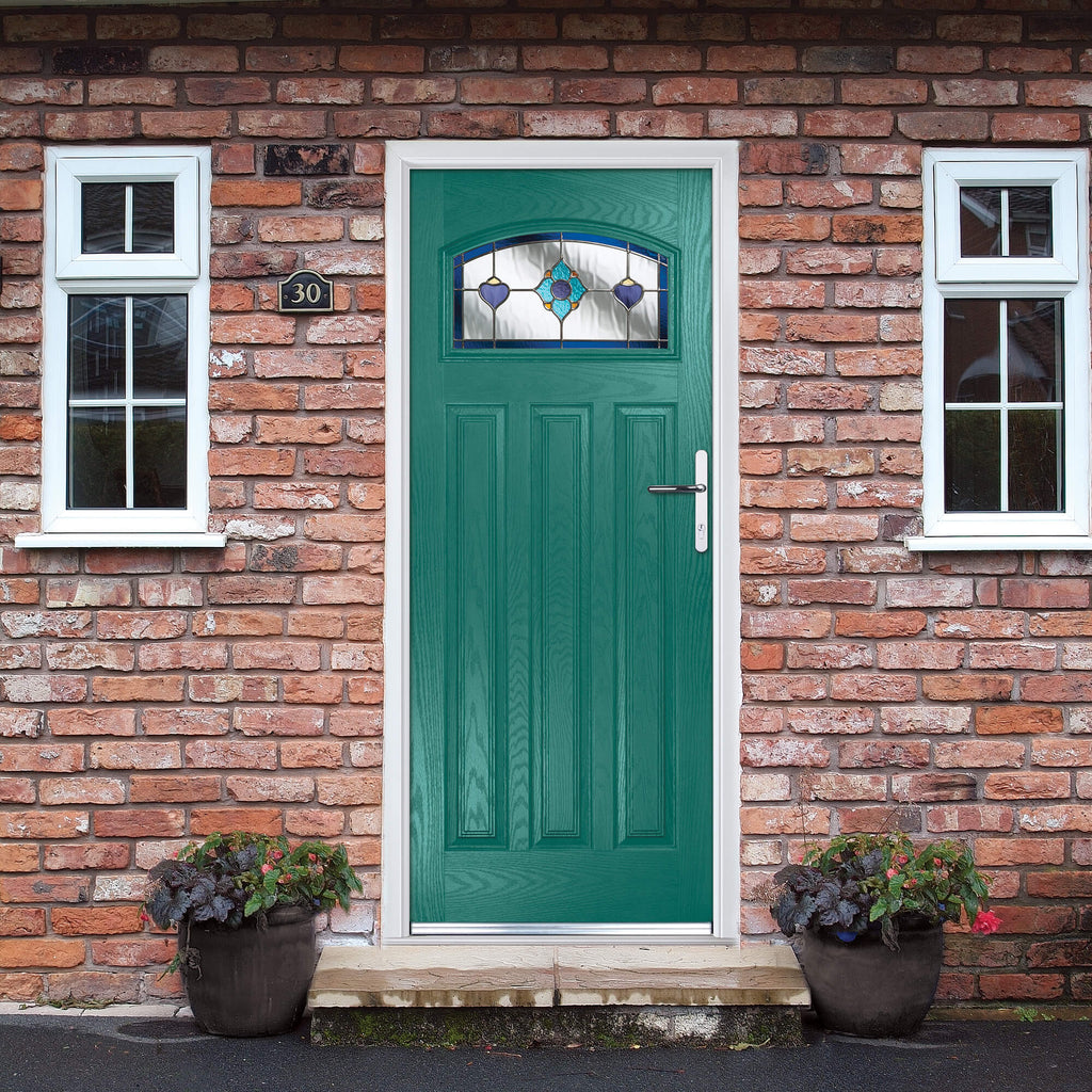 A dark green Edwardian Composite GRP Door with decorative glazed glass in a home front brick exterior