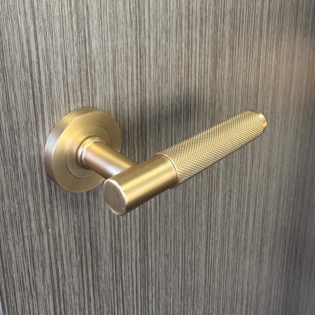 Close-up of a Knurled Satin Brass handle on a Flush Urban Grey 35mm Internal Laminate Door.