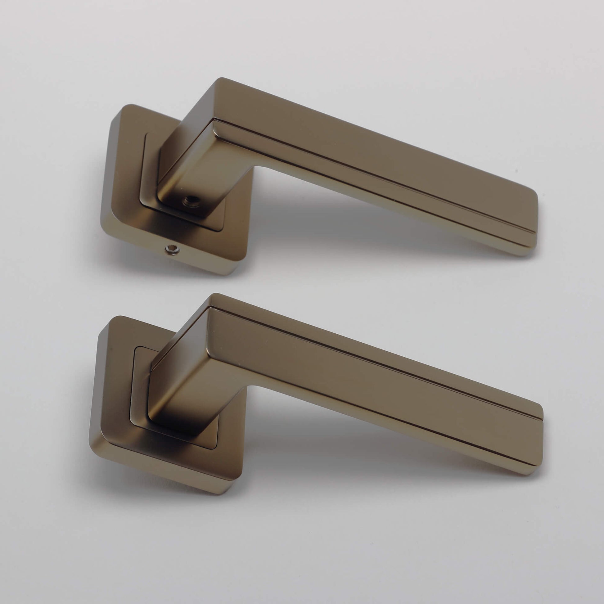A side view of a pair of Hermes Matt Coffee Square Rose Handles on a grey background.