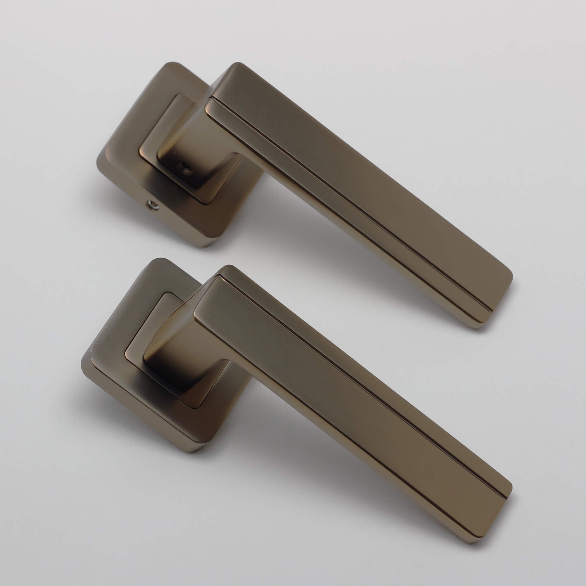 An angled view of a pair of Hermes Matt Coffee Square Rose Handles on a grey background.