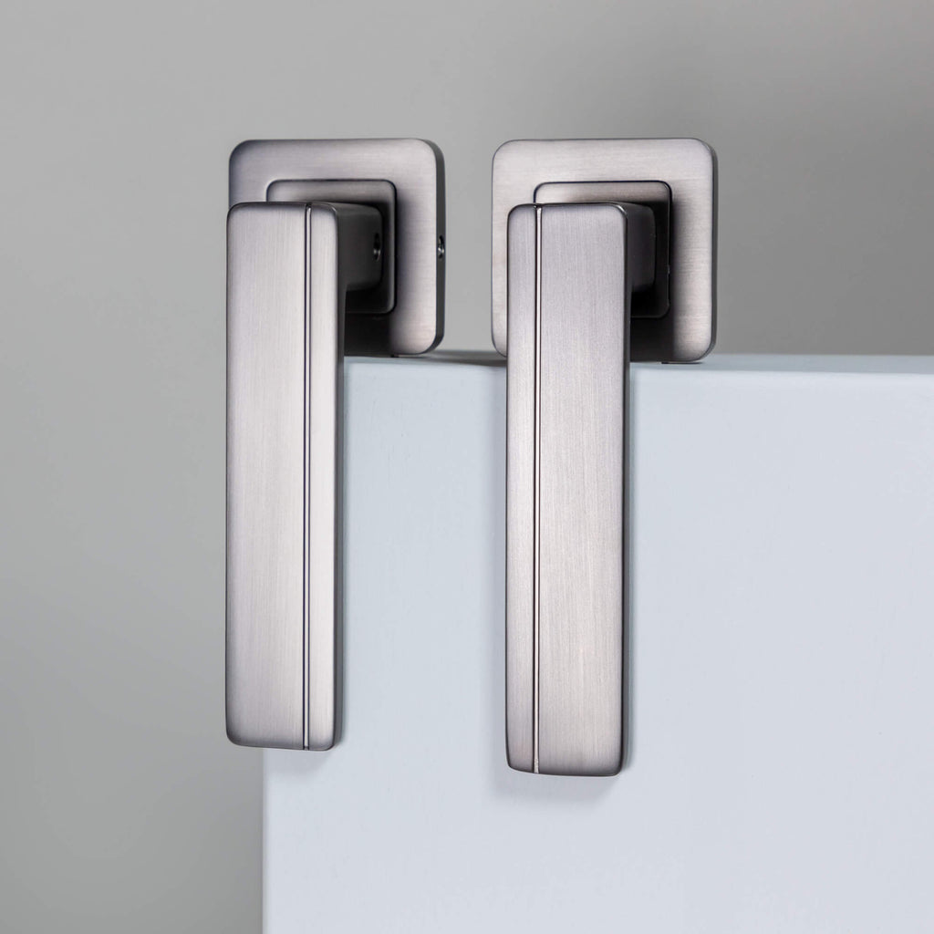 A pair of Hermes Matt Satin Black Square Rose Handles on a neutral background