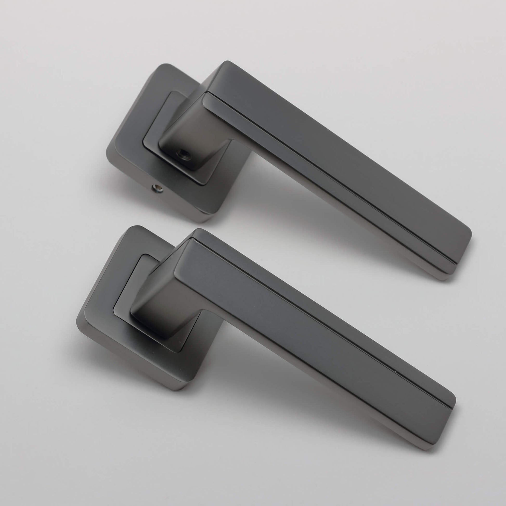 An angled view of a pair of Hermes Matt Satin Black Square Rose Handles on a light grey background.