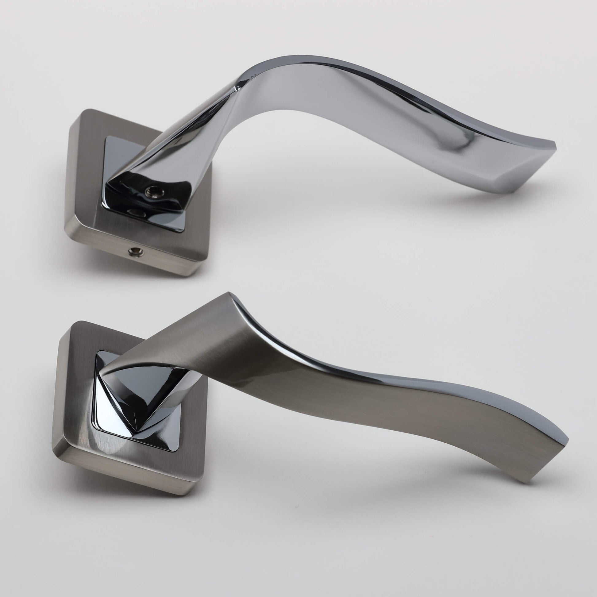 A side view of a pair of Incus Nickel Brushed & Polished Chrome Square Rose door handles on a light grey background.