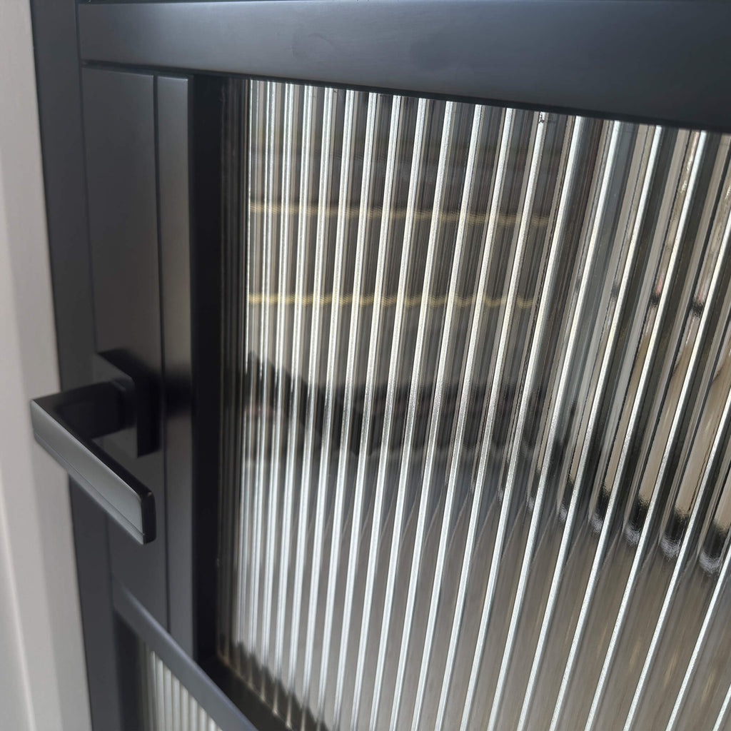 Close-up of a mA Kew Black Primer Plus 5 Lite Reeded Glass Door and a Hermes Flat Black handle.