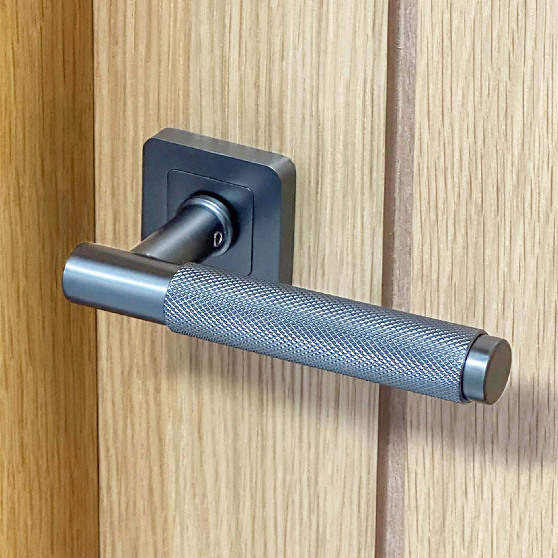 Matt satin black Metal door handle on a wooden door 