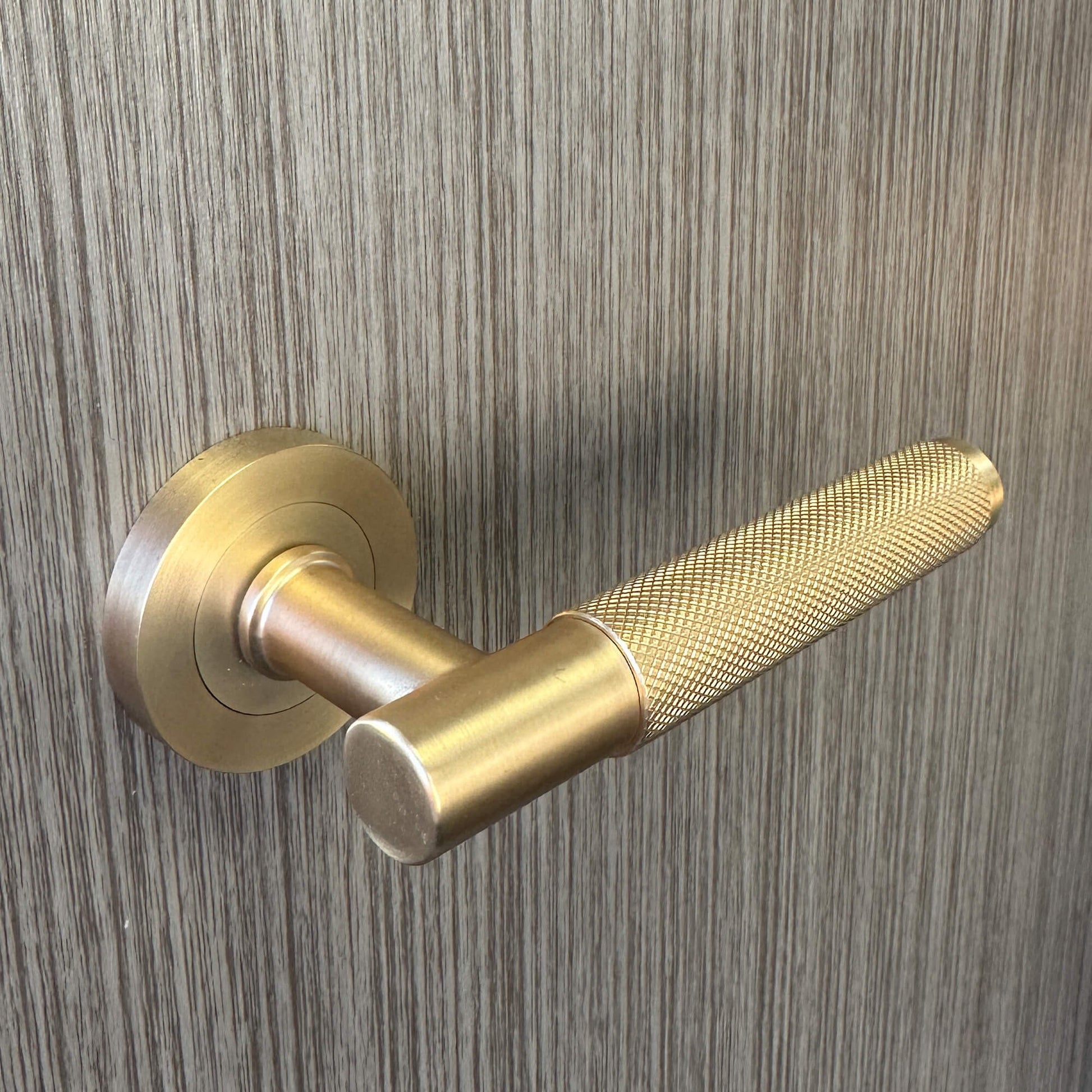 A Knurled Satin Brass door handle on a wooden door