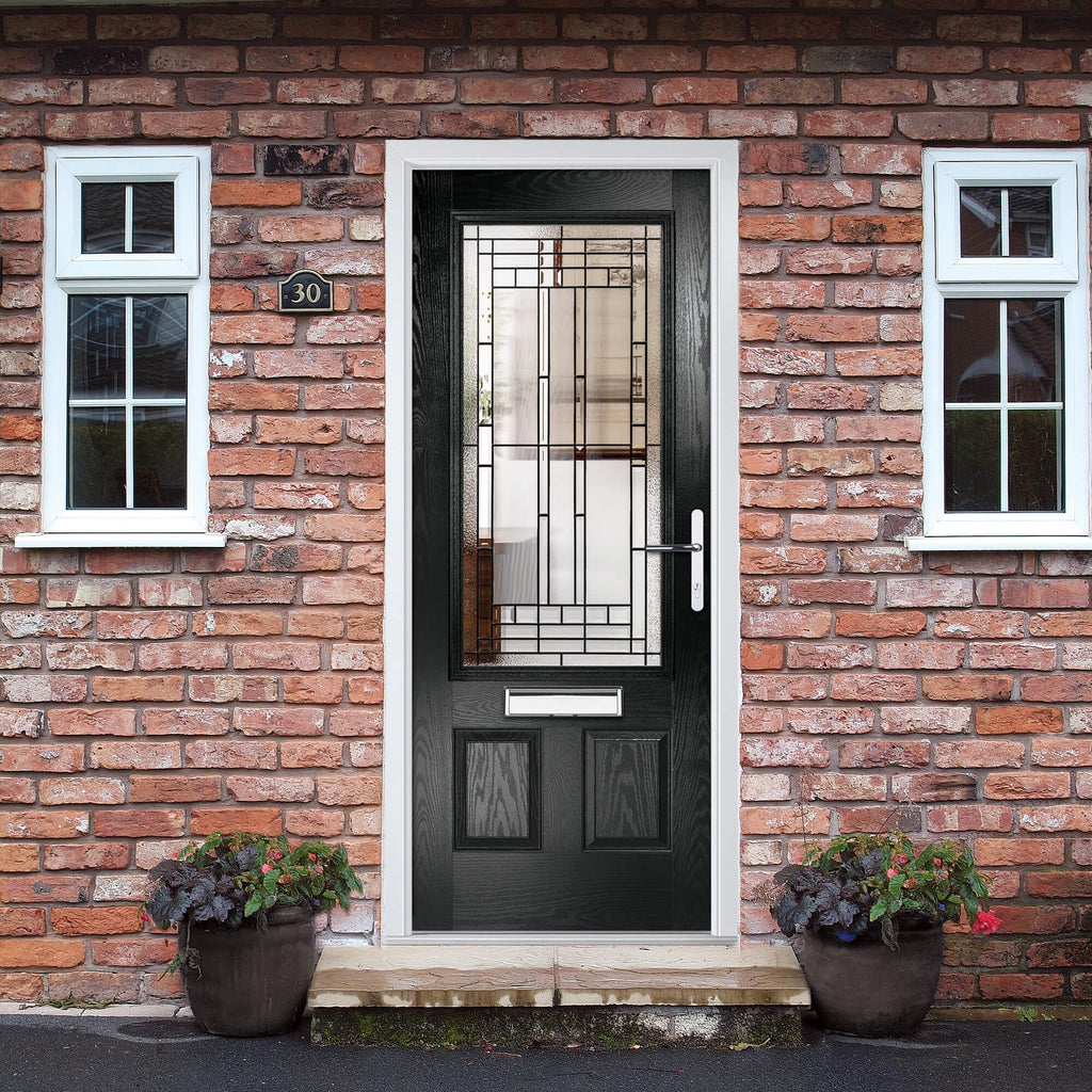 A black Lincoln Composite GRP External Door with decorative glass panel on a brick front home entrance.