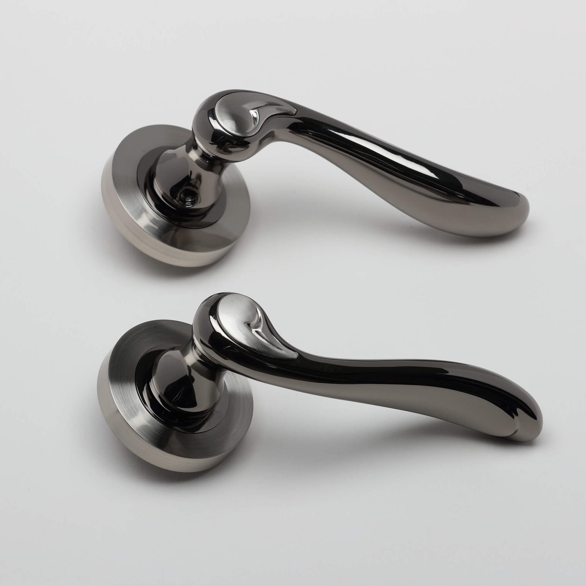A side view of a pair of Monet Black Nickel & Nickel Brushed Round Rose Door Handle on a white background.