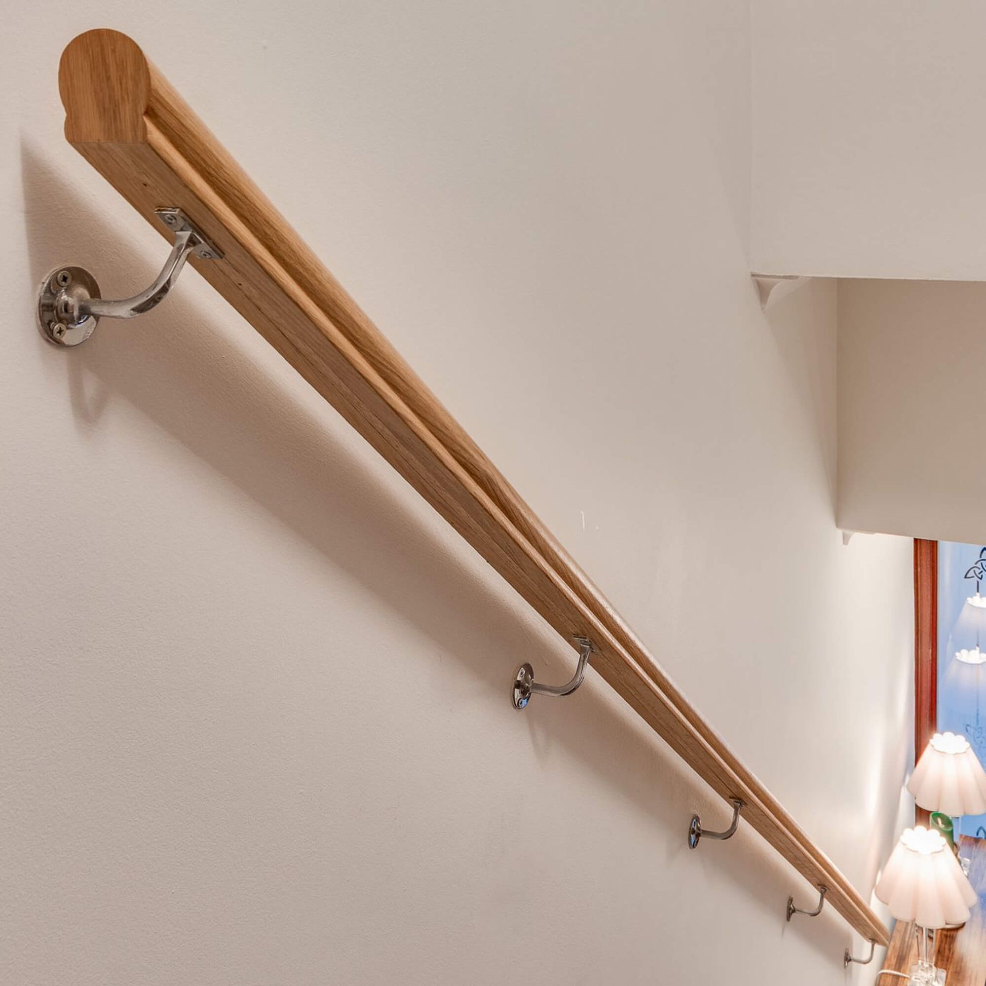 An Oak Veneered (13mm Infill) Handrail  with metal brackets on a beige wall.
