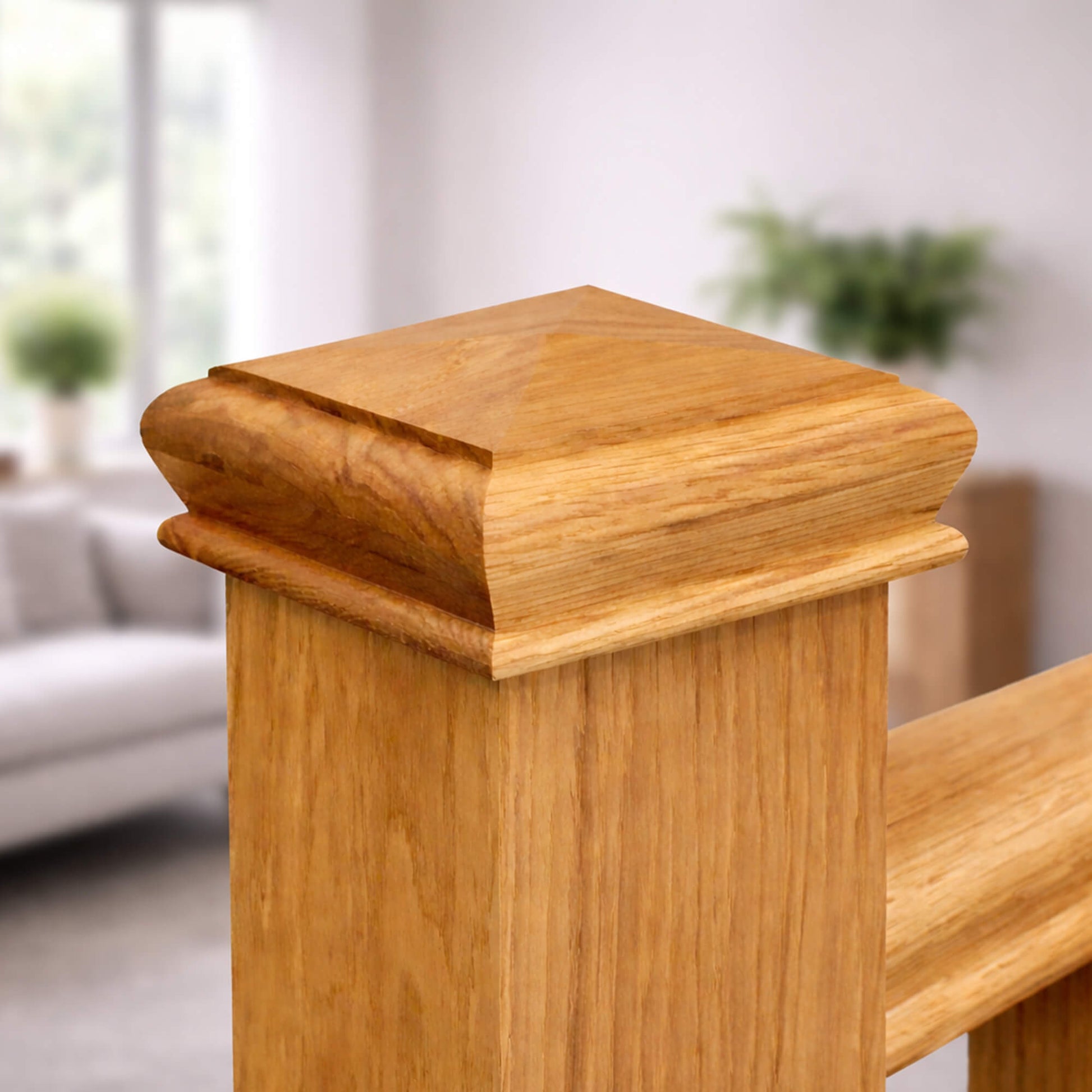 An Oak Pyramid Newel Cap on an oak new  post with a blurred indoor background