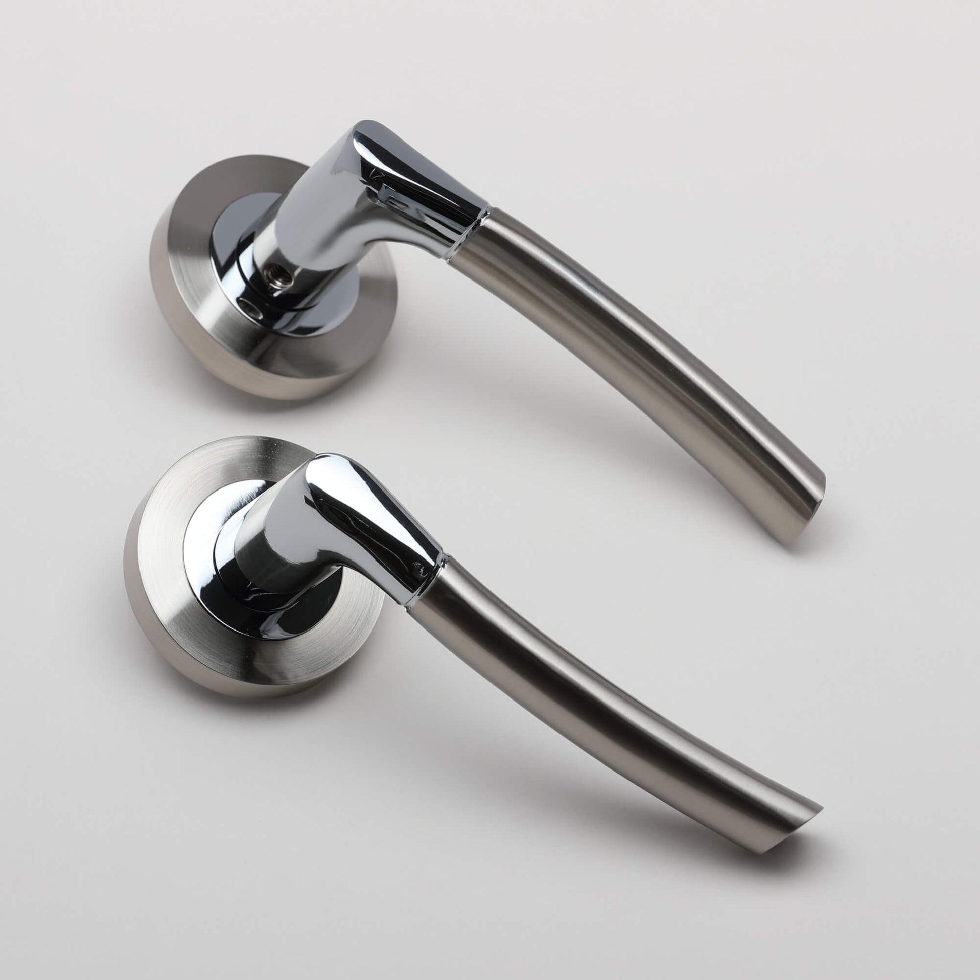 An angled view of Storm Nickel Brushed & Polished Chrome door handles on a grey background.