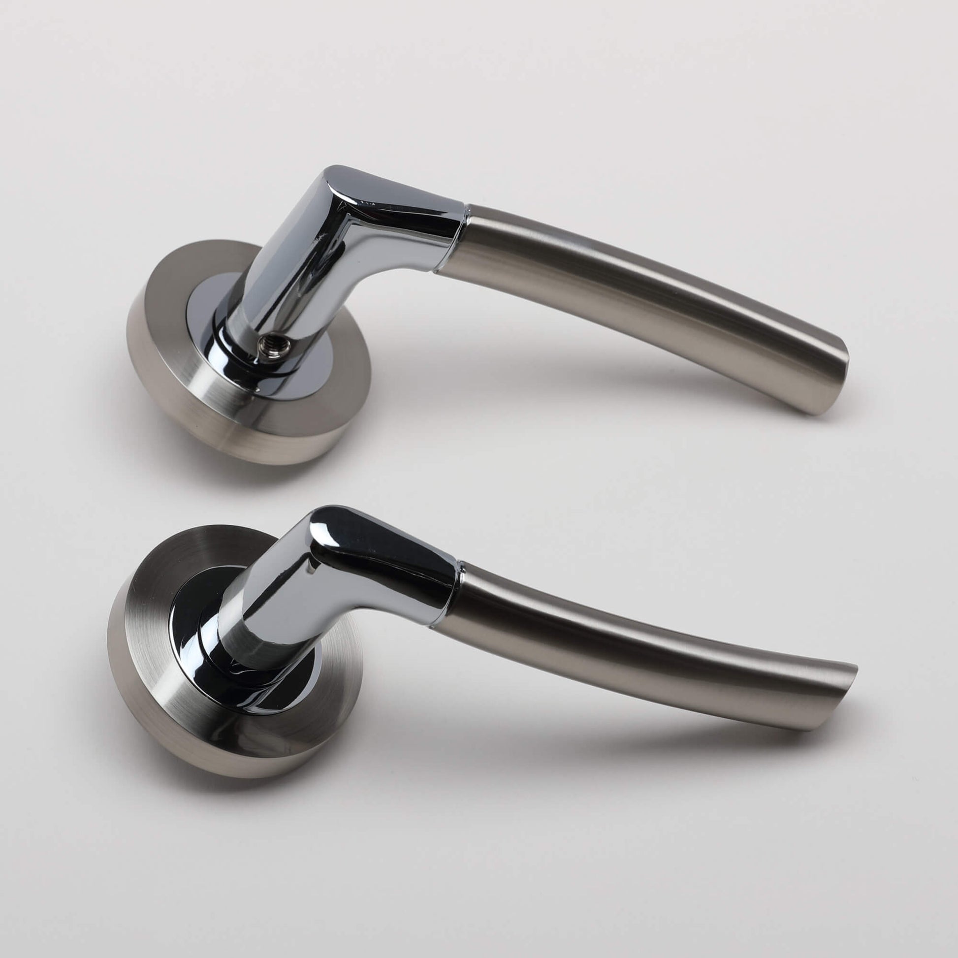A side view of Storm Nickel Brushed & Polished Chrome door handles on a grey background.