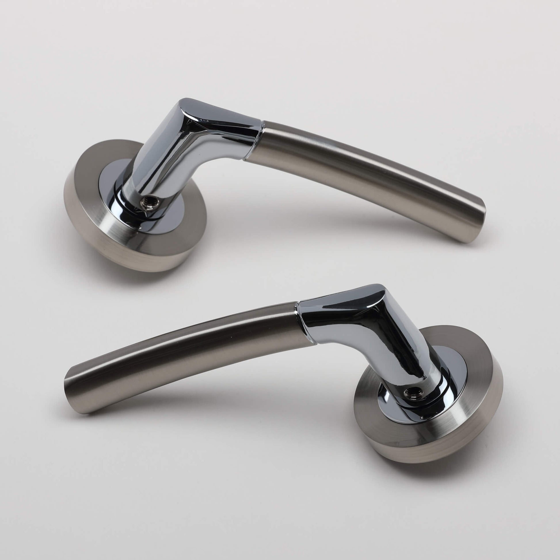 Pair of Storm Nickel Brushed & Polished Chrome door handles on a grey background.