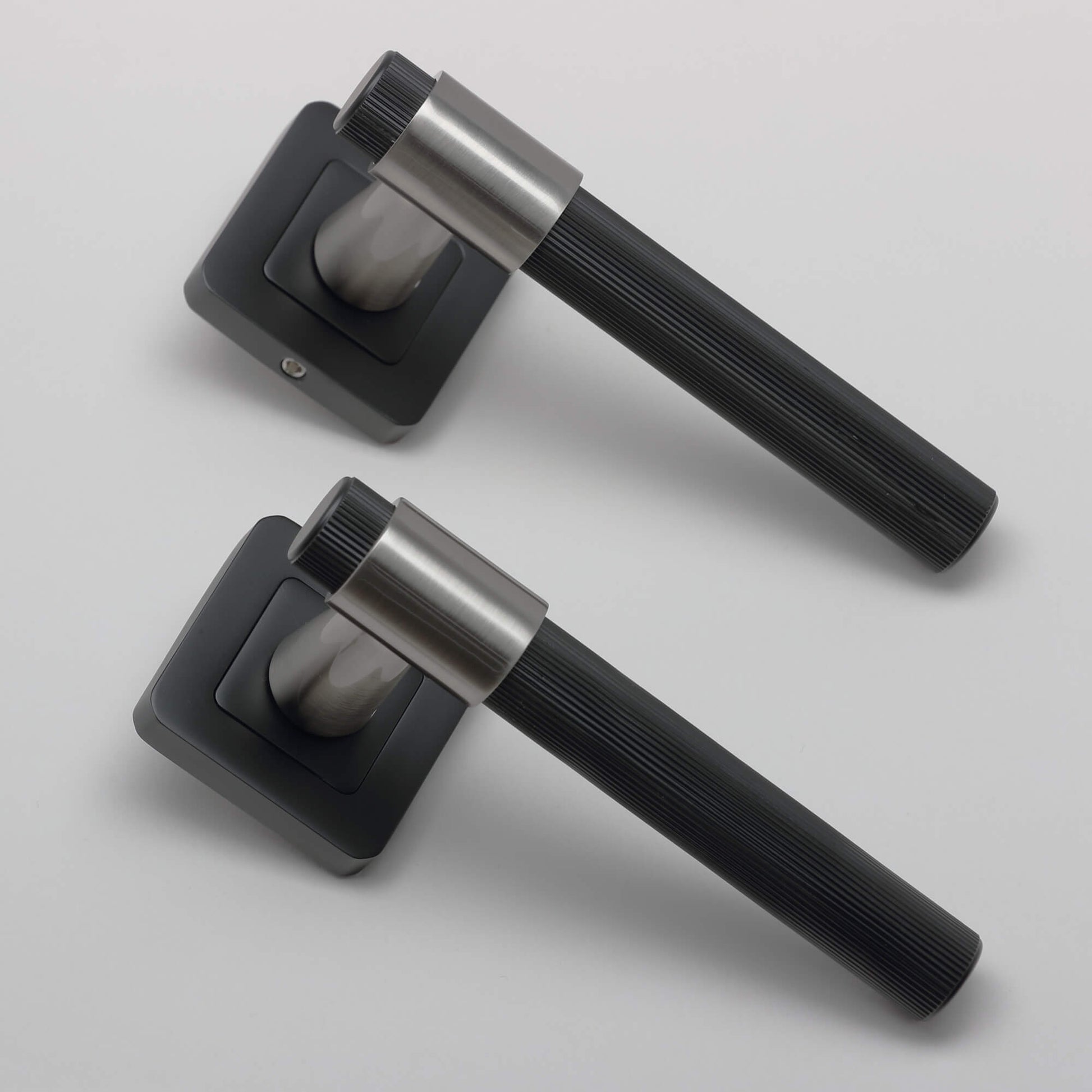 Angled view of a pair of A Stratus Flat Black & Nickel Brushed Square Rose Handle on a light grey background.