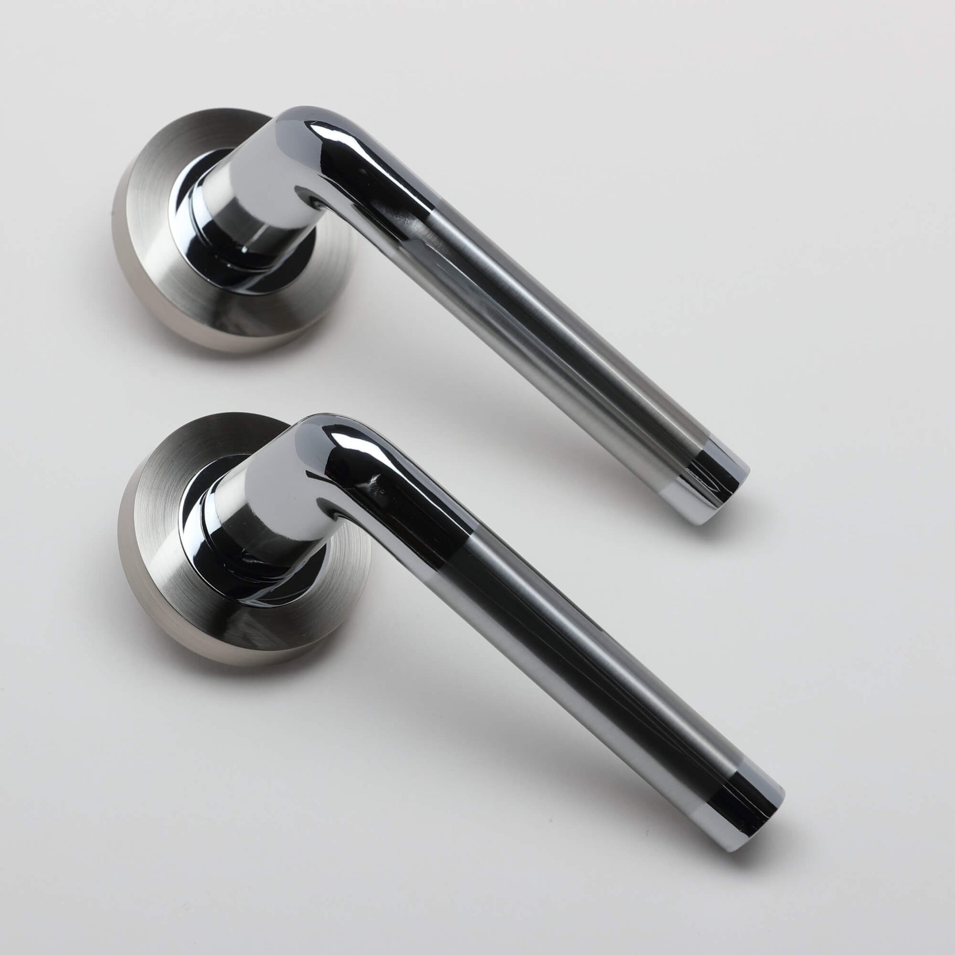 An angled view of a pair of Tempest Nickel Brushed & Polished Chrome door handles on a grey background.