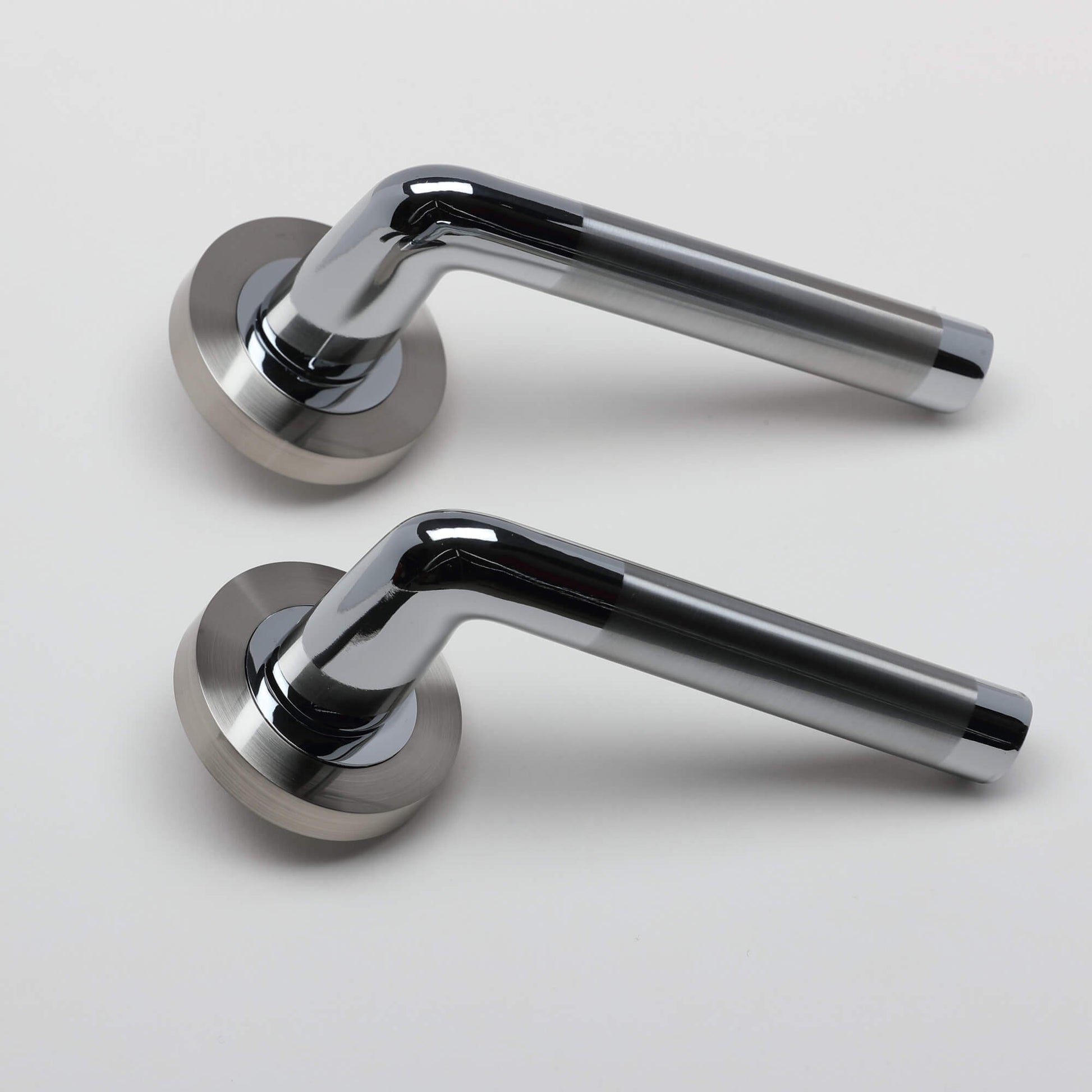 A side view of a pair of Tempest Nickel Brushed & Polished Chrome door handles on a grey background.