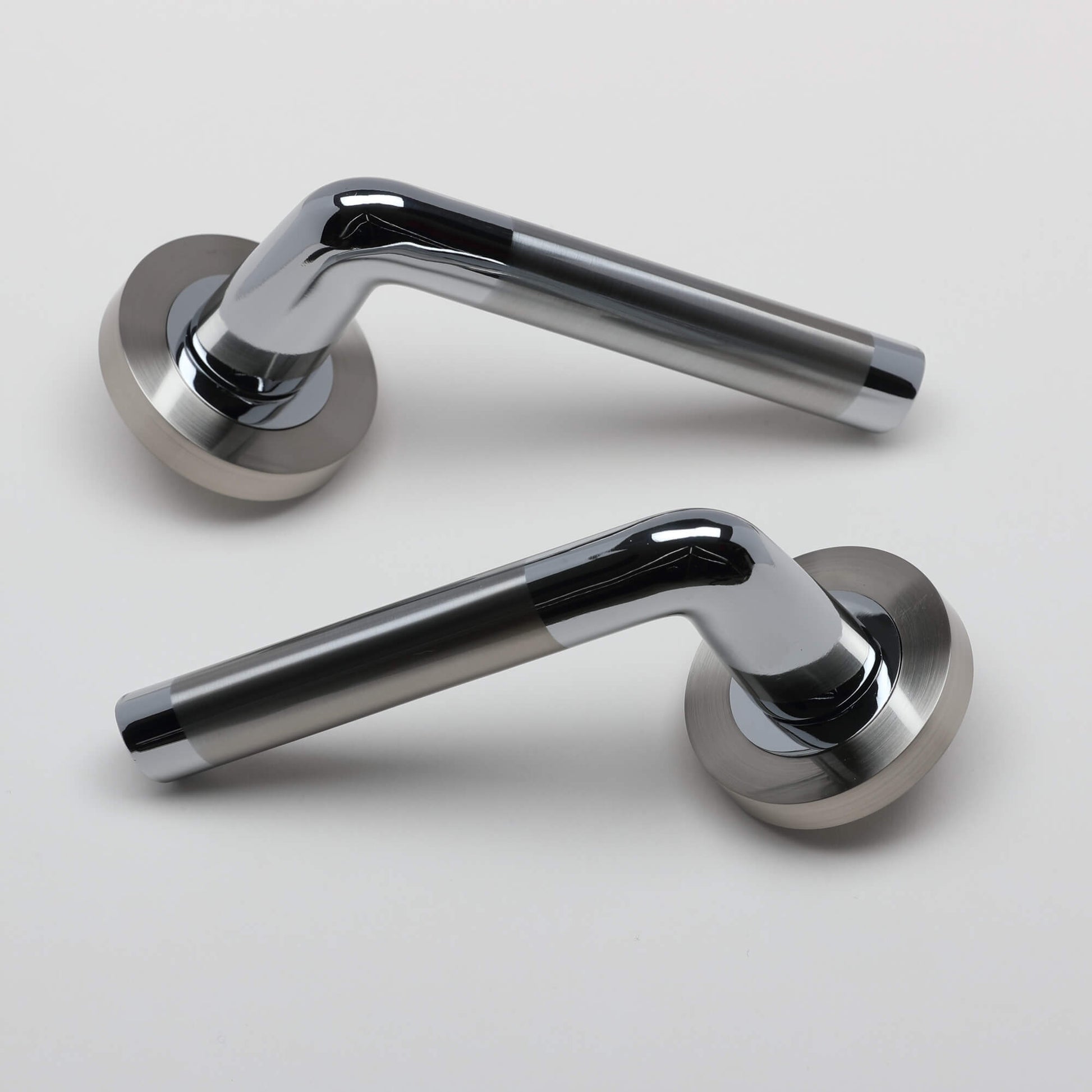 A pair of Tempest Nickel Brushed & Polished Chrome door handles on a grey background.