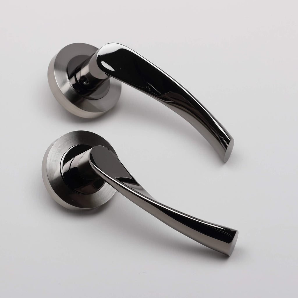 Angled view of a pair of Trade Range Black Nickel & Nickel Brushed Door handles on a light grey background.