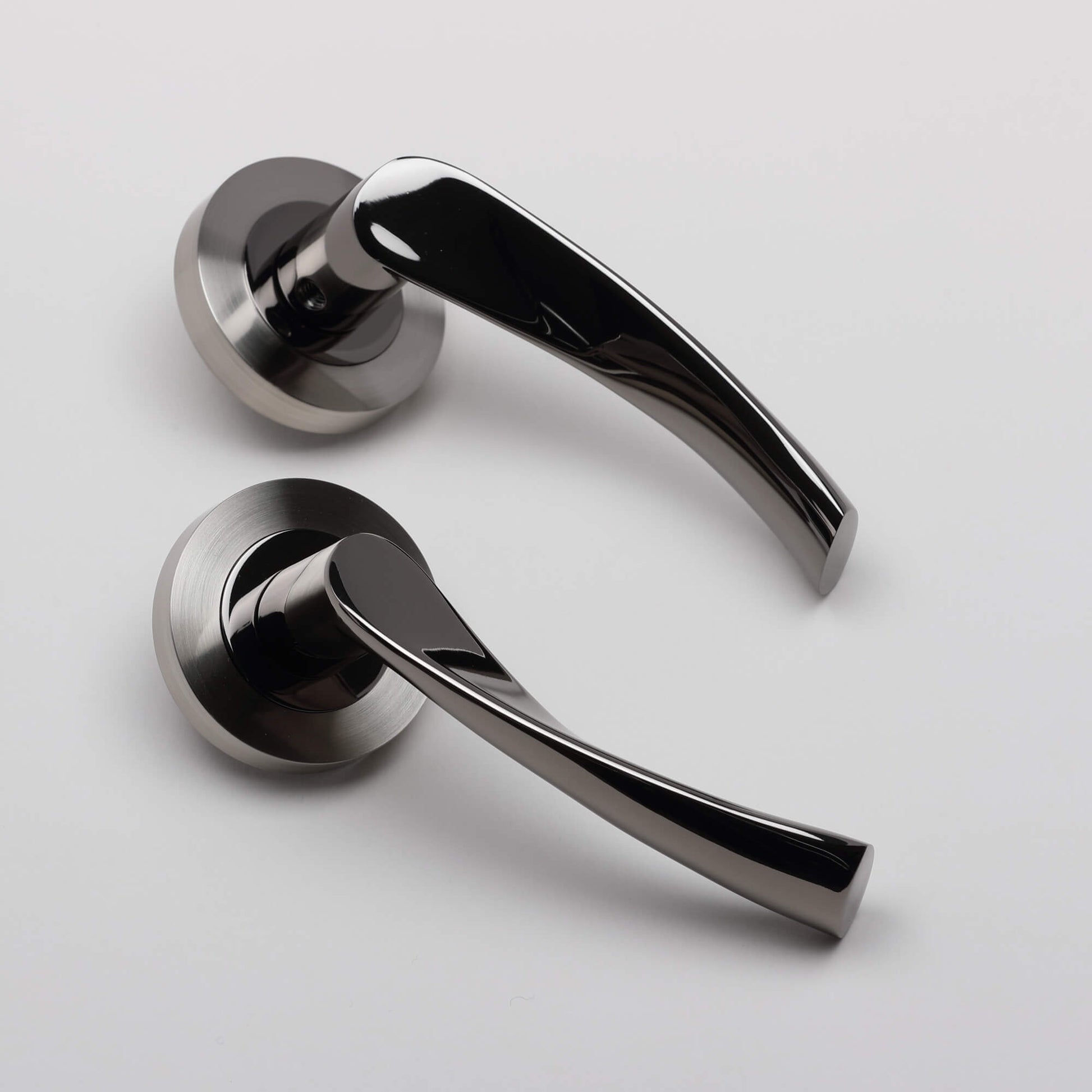 Angled view of a pair of Trade Range Black Nickel & Nickel Brushed Door handles on a light grey background.