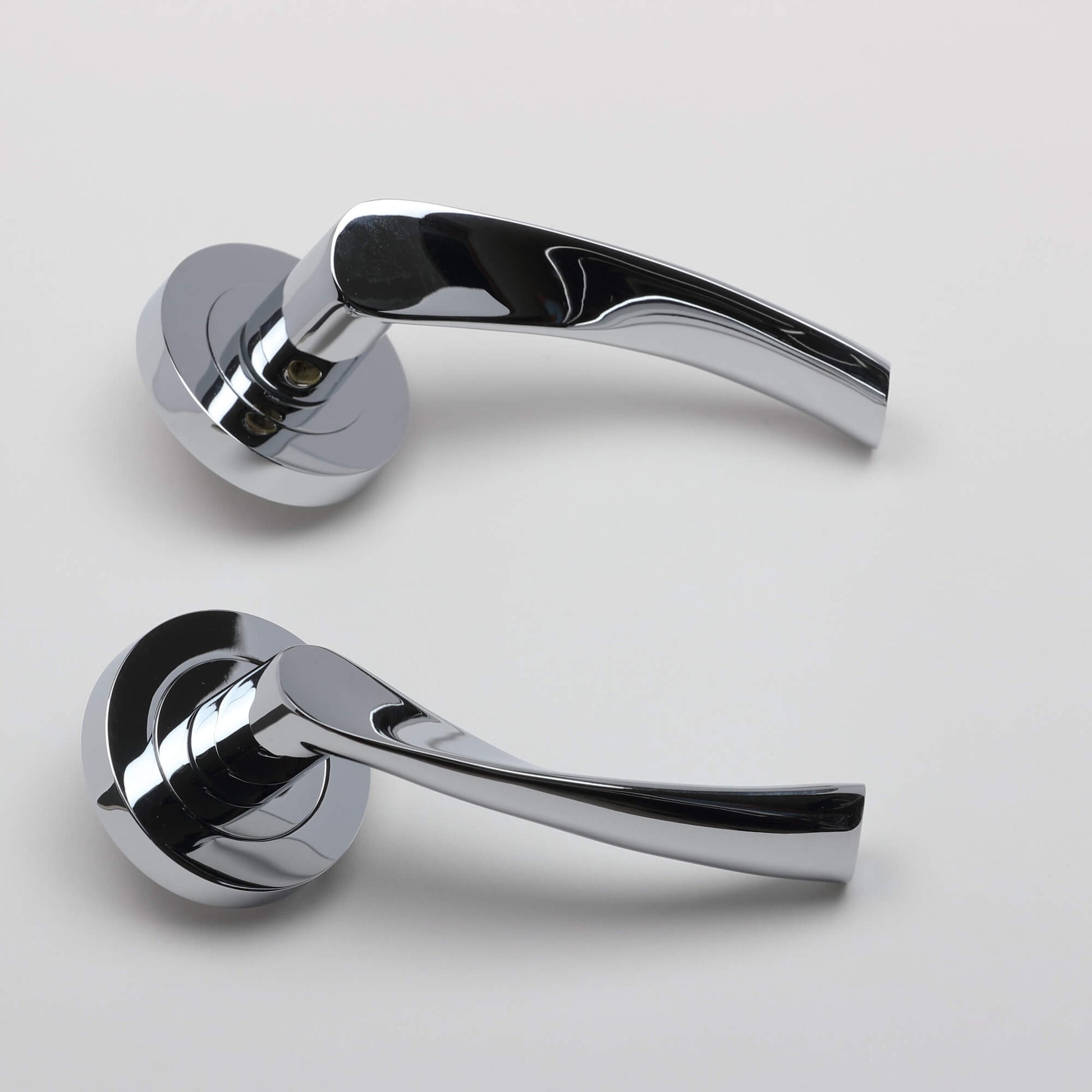 A side view of a pair of Trade Range Polished Chrome door handles on a grey background.