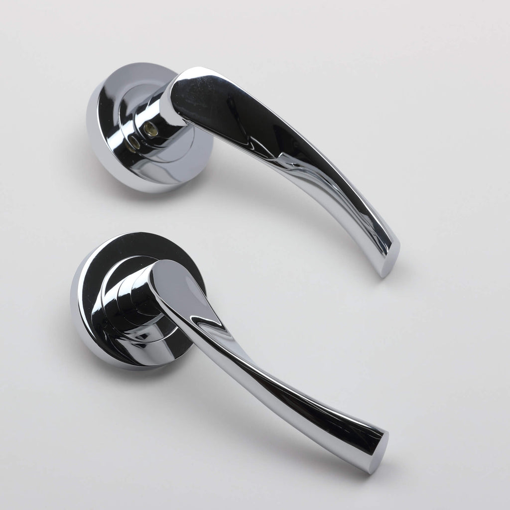 An angled view of a pair of Trade Range Polished Chrome door handles on a grey background.