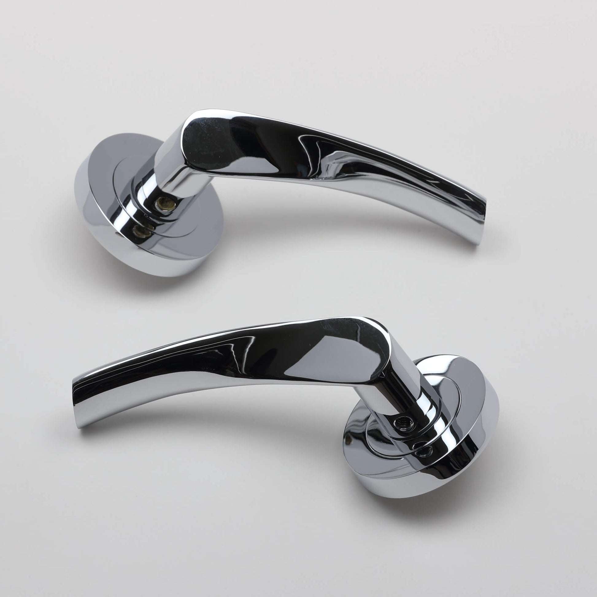 A pair of Trade Range Polished Chrome door handles on a grey background.