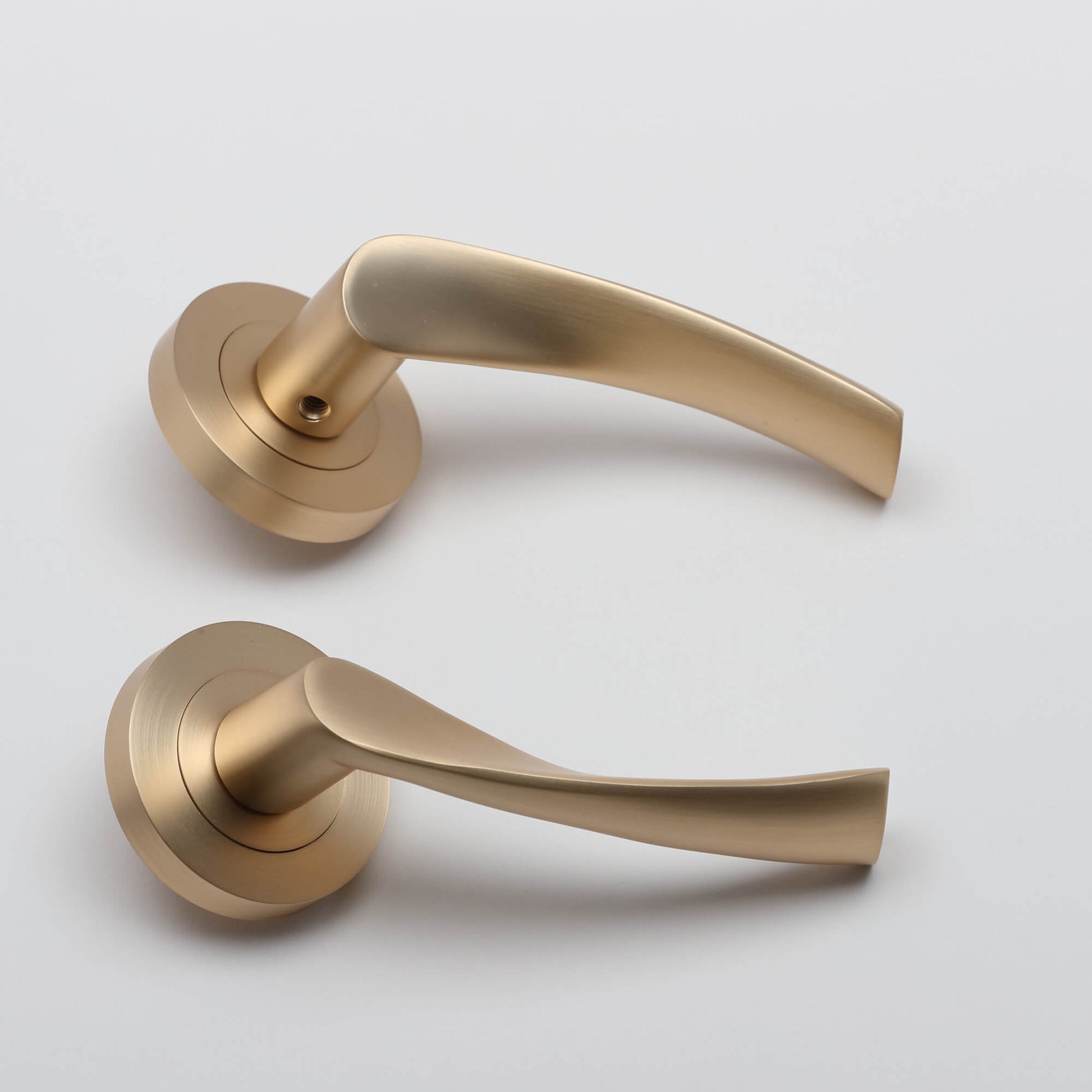 A side view of a pair of Trade Range Satin Brass Handles on a grey background.