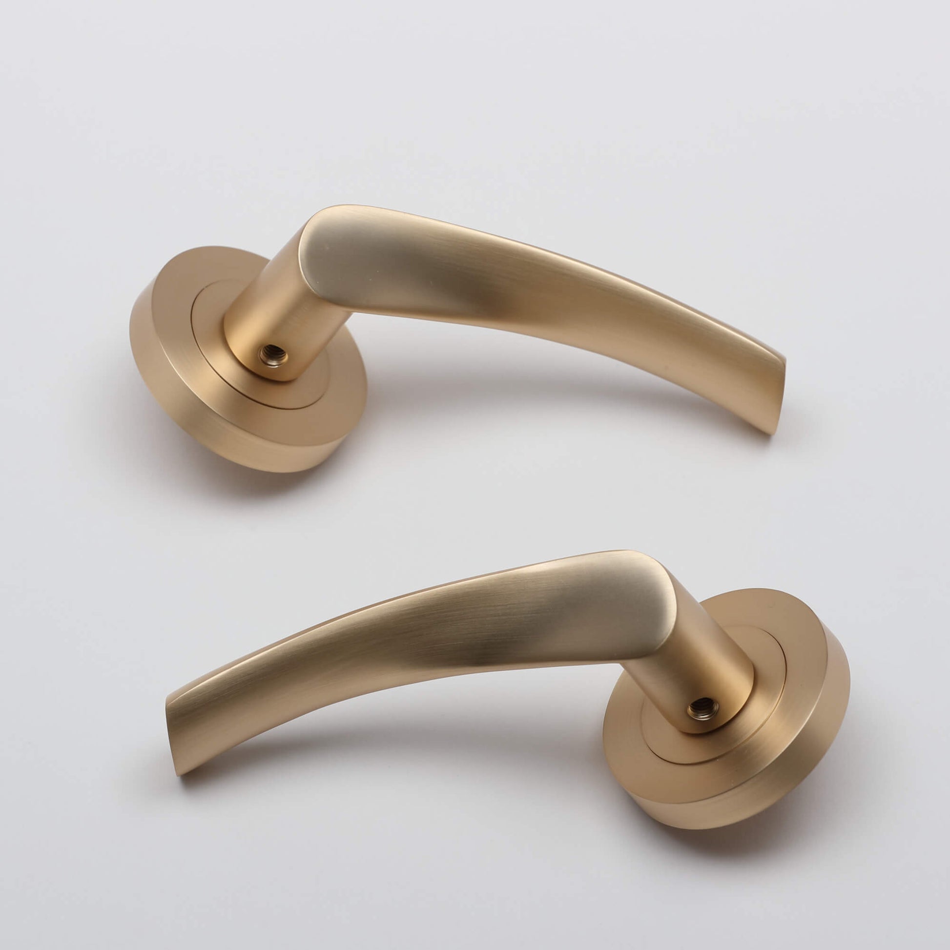 A pair of Trade Range Satin Brass Handles on a grey background.