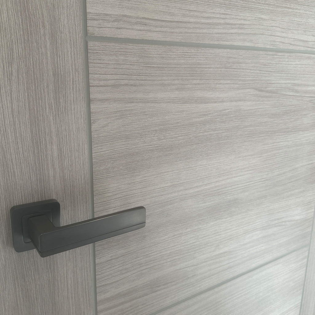 Close-up of the grooves and wood grain on a Vancouver Stone Grey 40mm Internal Laminate Door with a Flat Black Hermes Handle.