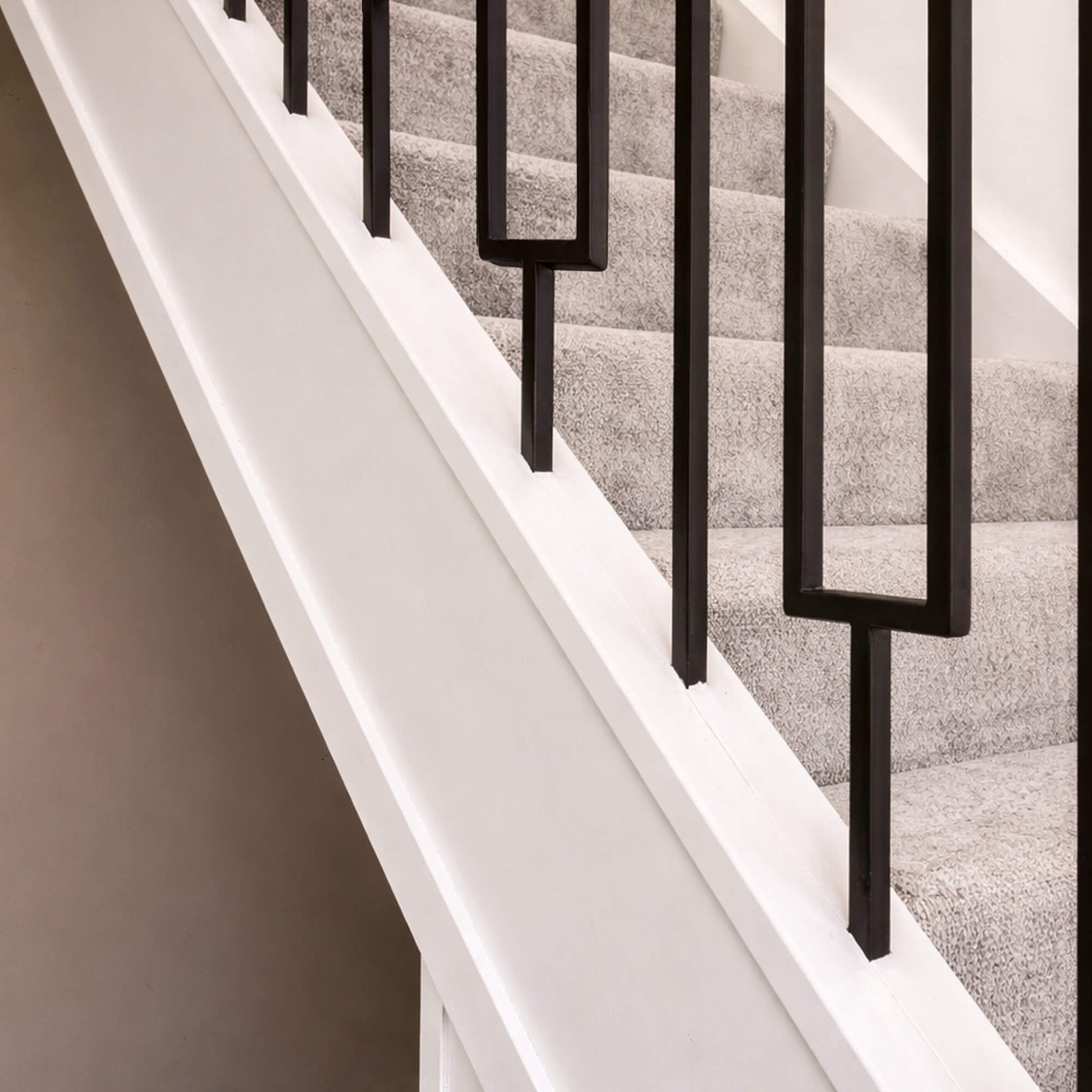 White Primed Staircase with White Primed Baserail (13mm Infill) and black rectangle spindles and grey carpeted steps.
