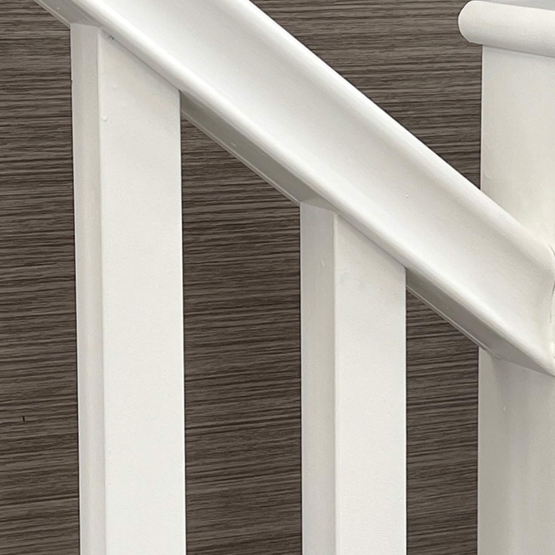 Close-up of a staircase with white primed blank spindles and handrail.