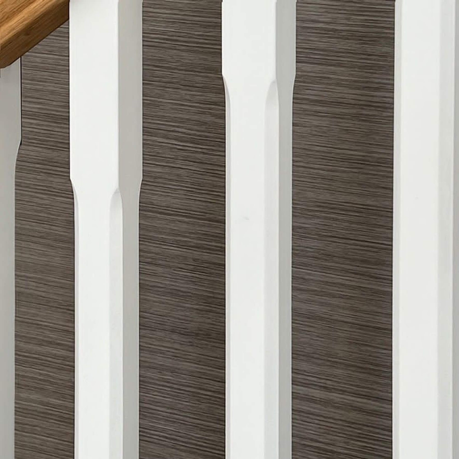 Close-up of White Primed Chamfered Spindles with a wallpapered background