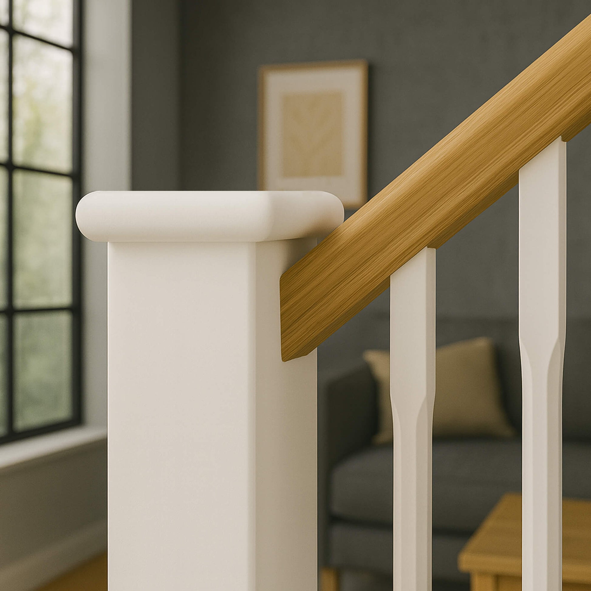 Close-up of a staircase with wooden handrail and white primed chamfered spindles and a White Primed Flat Newel Cap with blurred background of a living room.