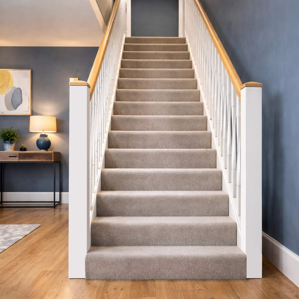 A carpeted staircase with White Primed Roma Spindles and White Primed Blank Newel Posts with oak pyramid new caps in a home setting.