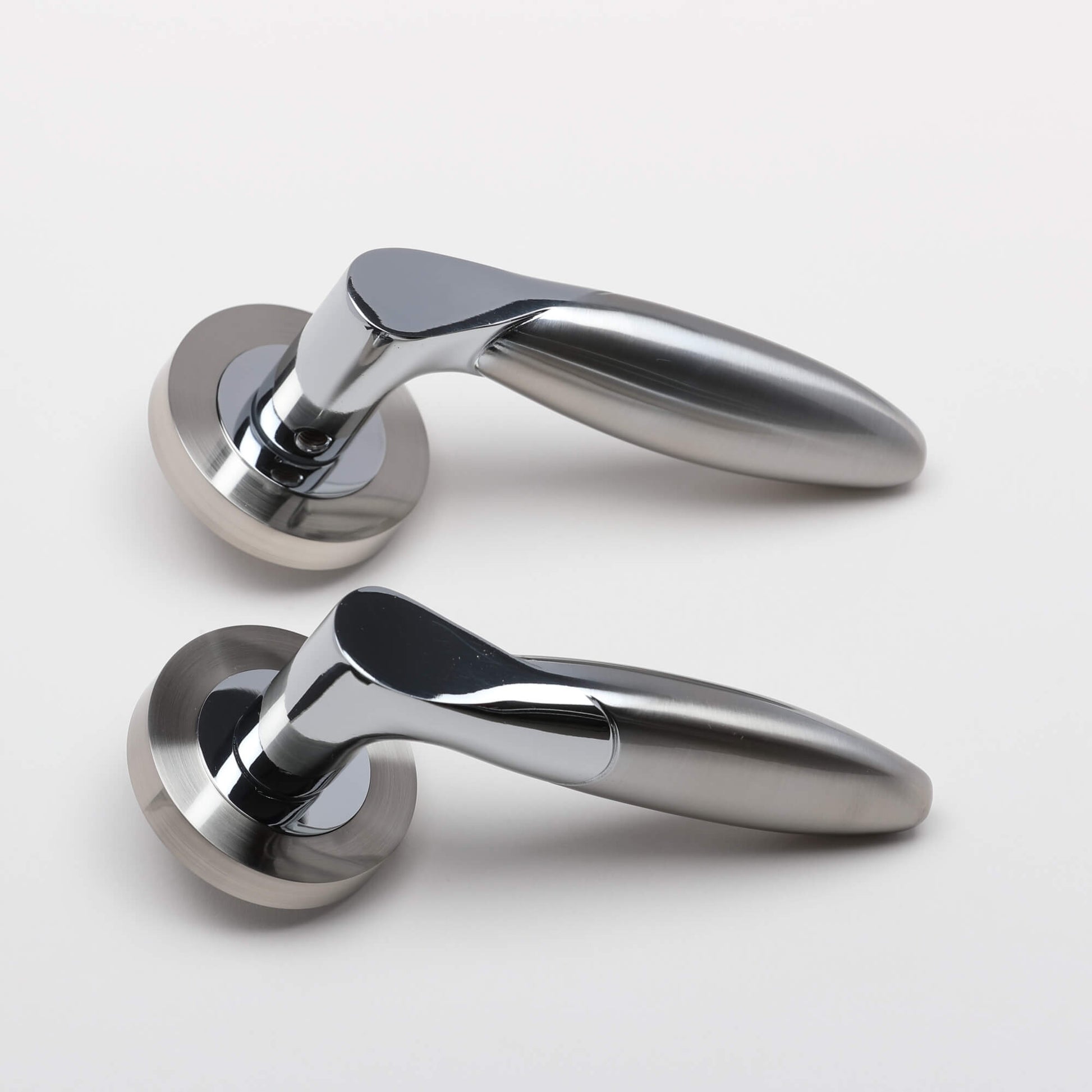 A side view of a set of Zeus Nickel Brushed & Polished Chrome Handles on a grey background